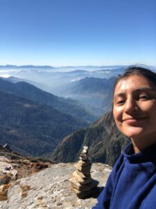 Photo of Pooja smiling with background of nature behind her